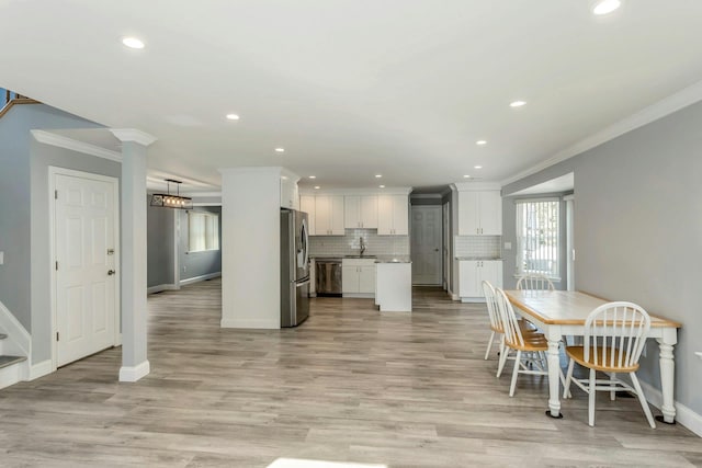 dining area featuring crown molding, sink, and light hardwood / wood-style flooring