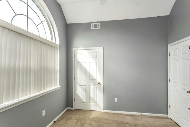 unfurnished bedroom with light colored carpet and lofted ceiling