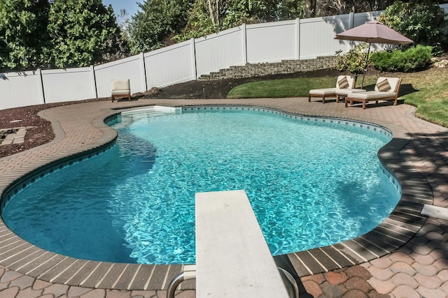 view of pool with a diving board and a patio area