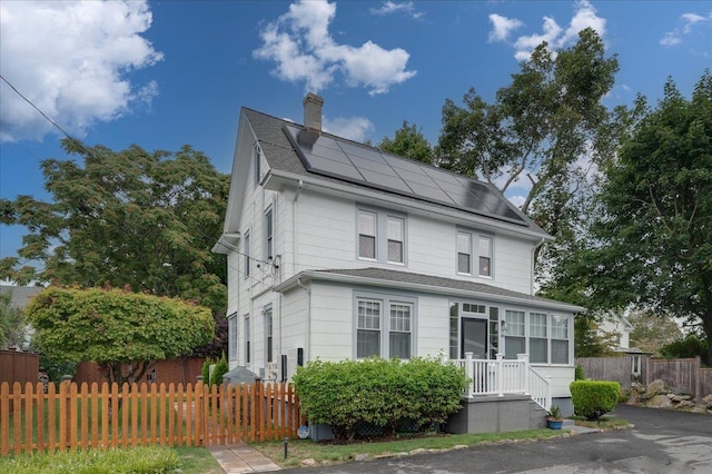 american foursquare style home with fence private yard, a chimney, and solar panels