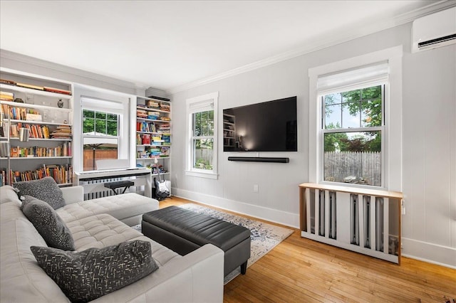 living area with a wall mounted air conditioner, crown molding, light wood-style flooring, and baseboards