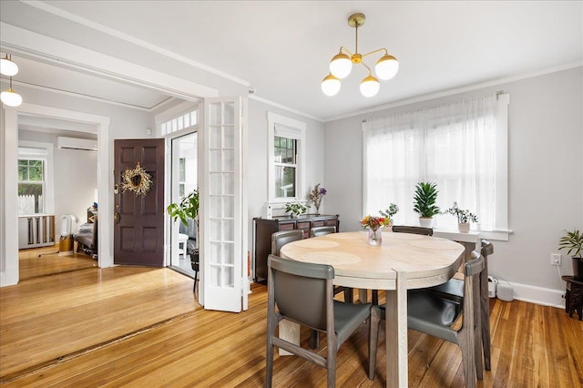 dining space with a chandelier, wood finished floors, baseboards, ornamental molding, and radiator