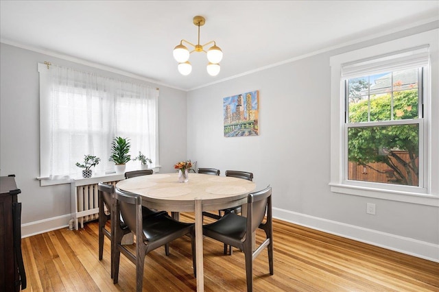 dining room featuring light wood-type flooring, crown molding, baseboards, and an inviting chandelier