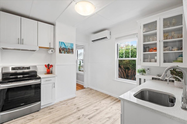 kitchen featuring electric range, a wall mounted air conditioner, a sink, and white cabinets