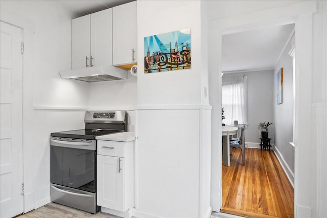 kitchen featuring light wood-style floors, electric stove, light countertops, under cabinet range hood, and white cabinetry