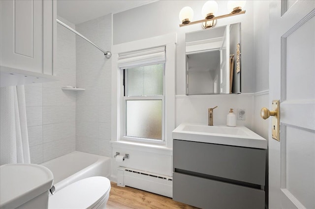 full bath featuring plenty of natural light, a baseboard radiator, wood finished floors, and toilet