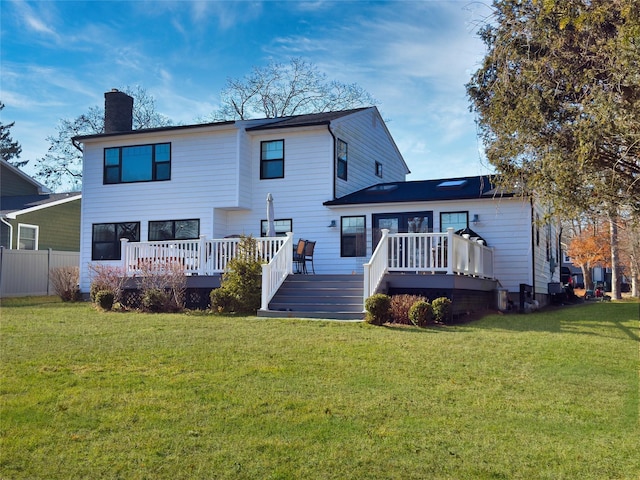 back of property featuring a wooden deck and a lawn