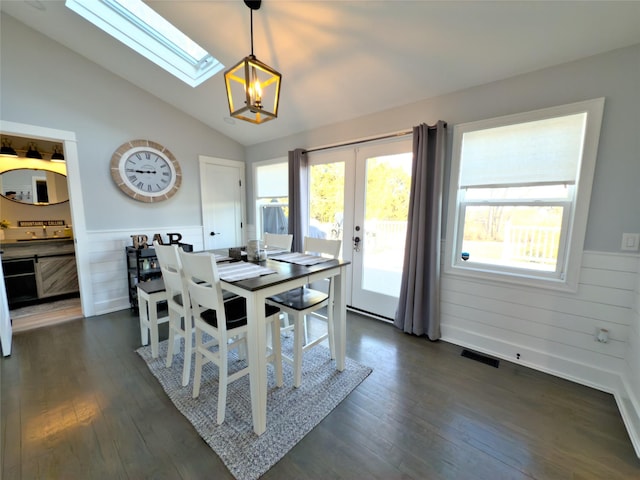 dining area with plenty of natural light, dark wood-type flooring, and vaulted ceiling with skylight