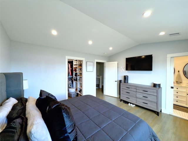 bedroom featuring hardwood / wood-style flooring, vaulted ceiling, and connected bathroom