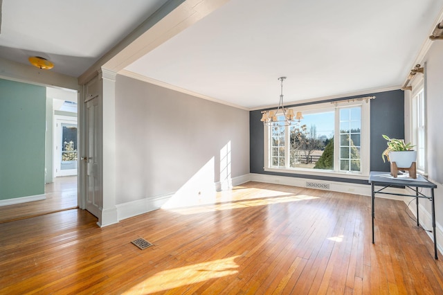 unfurnished dining area with an inviting chandelier, hardwood / wood-style flooring, and ornamental molding