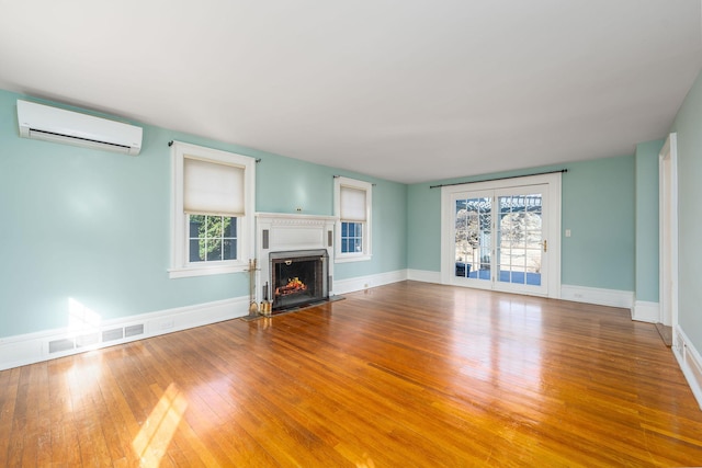 unfurnished living room with wood-type flooring and a wall mounted air conditioner