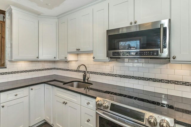 kitchen with sink, dark stone counters, white cabinets, and appliances with stainless steel finishes