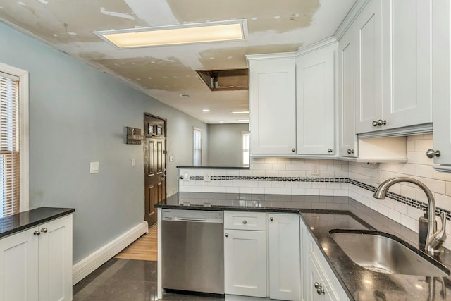 kitchen featuring sink, tasteful backsplash, white cabinets, stainless steel dishwasher, and dark stone counters