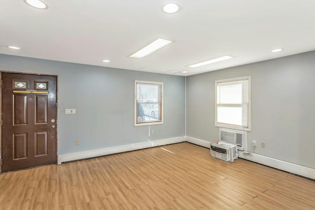 spare room featuring a wall unit AC and light hardwood / wood-style flooring