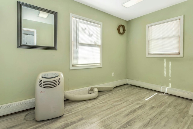 unfurnished room featuring a baseboard heating unit and light hardwood / wood-style floors