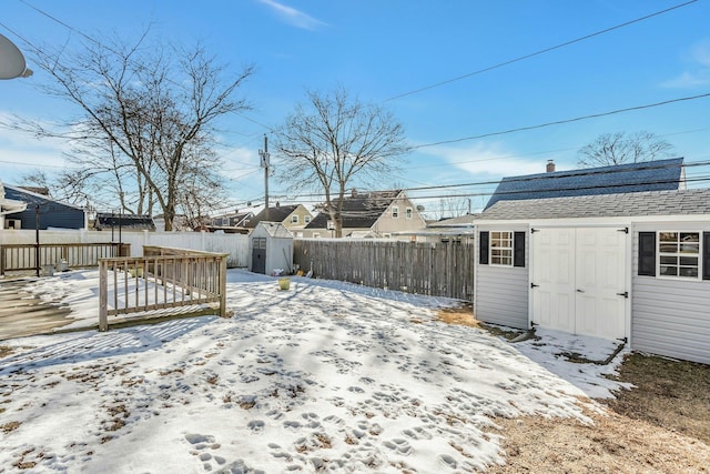 yard layered in snow with a wooden deck and a storage shed