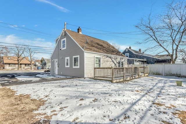 snow covered house with a wooden deck