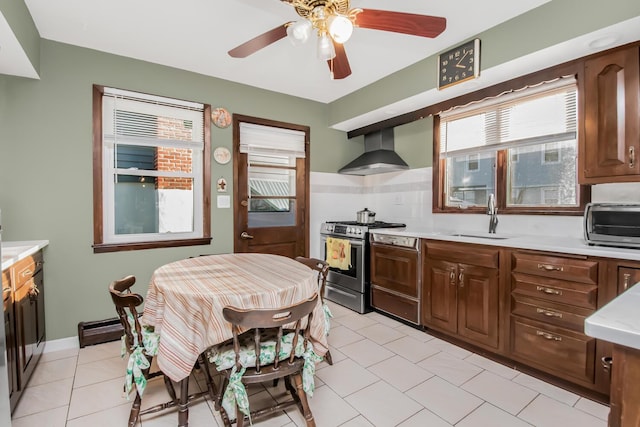 kitchen with stainless steel range with gas cooktop, sink, backsplash, light tile patterned floors, and wall chimney range hood