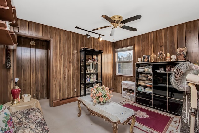 living room with light carpet, track lighting, ceiling fan, and wood walls