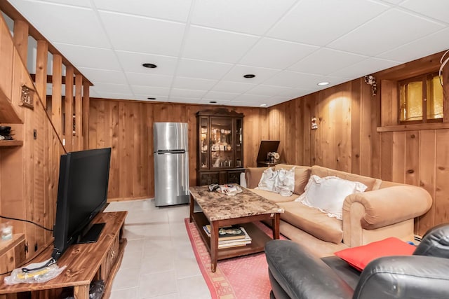 living room with light tile patterned flooring, wooden walls, and a drop ceiling