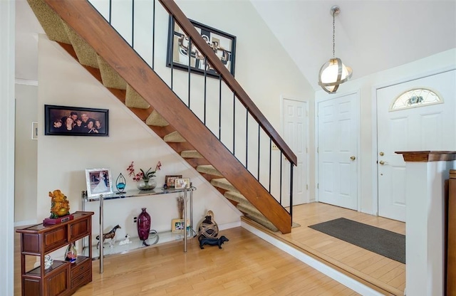 entrance foyer with wood-type flooring and high vaulted ceiling