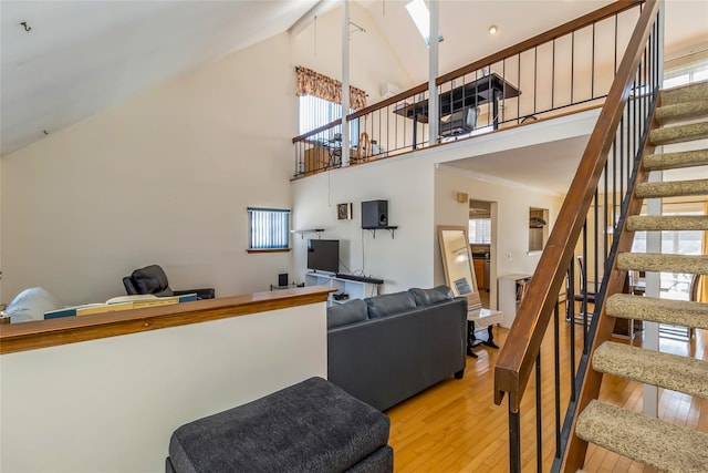 living room featuring ornamental molding, high vaulted ceiling, and light hardwood / wood-style flooring