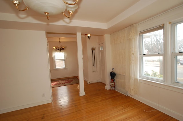 unfurnished room featuring an inviting chandelier and light wood-type flooring