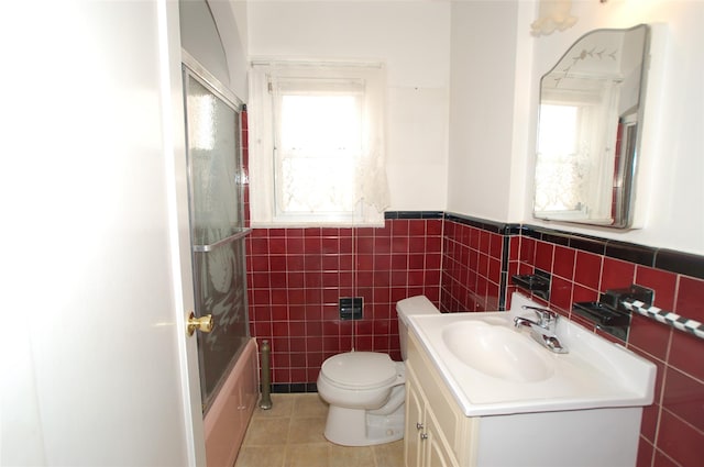 full bathroom featuring a healthy amount of sunlight, toilet, combined bath / shower with glass door, and vanity