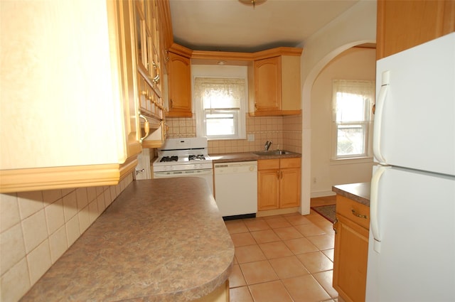 kitchen featuring sink, light tile patterned floors, white appliances, and decorative backsplash