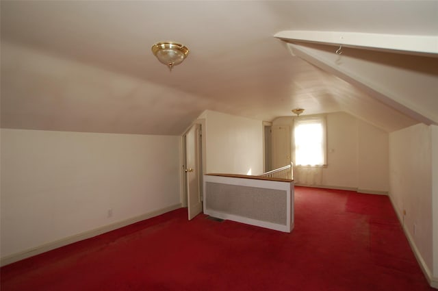 additional living space featuring dark carpet and vaulted ceiling