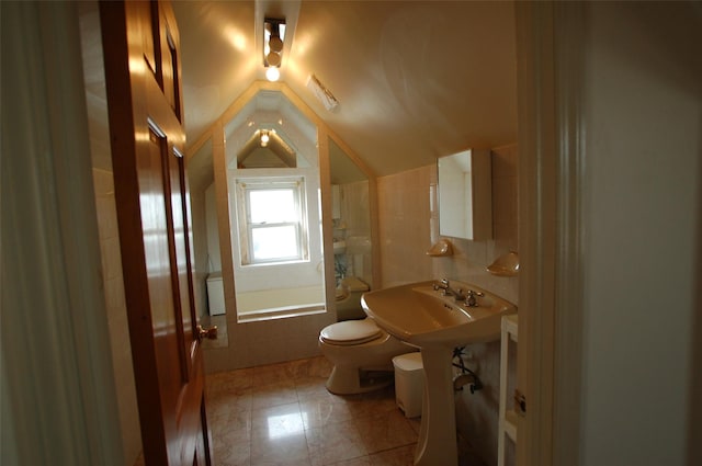 full bathroom with vaulted ceiling, sink, tile walls, tiled shower / bath combo, and toilet