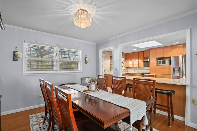 dining space featuring an inviting chandelier, hardwood / wood-style floors, a skylight, and ornamental molding