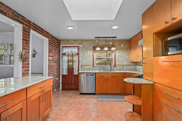 kitchen with backsplash, brick wall, appliances with stainless steel finishes, and a sink