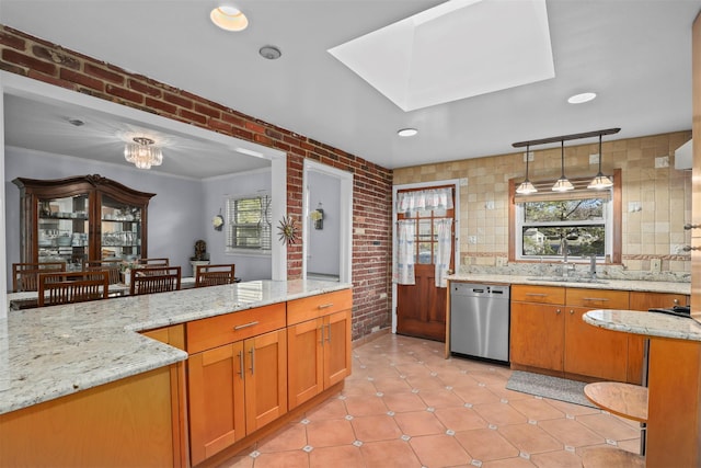 kitchen featuring sink, dishwasher, light stone counters, brick wall, and decorative light fixtures