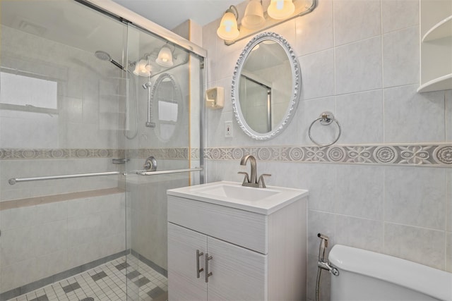 bathroom with vanity, toilet, tile walls, and a shower stall