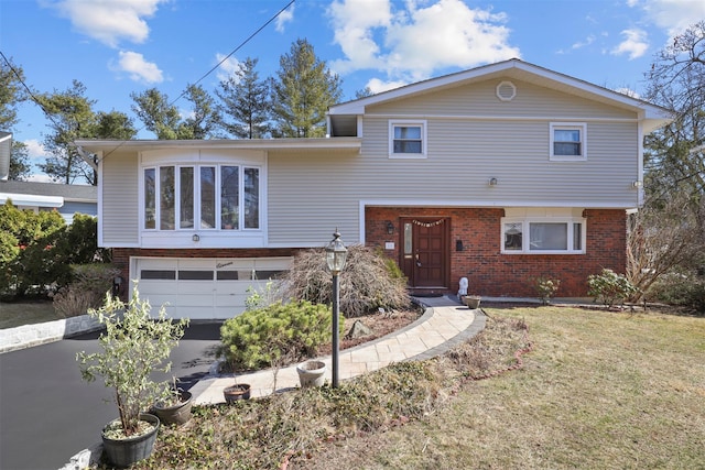 tri-level home featuring brick siding, an attached garage, driveway, and a front yard