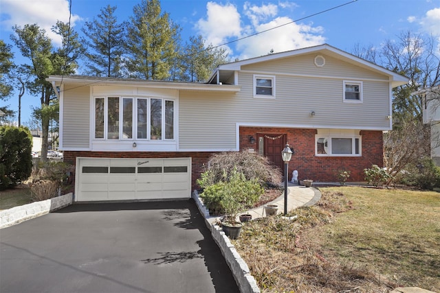 split level home with a garage, a front lawn, brick siding, and driveway