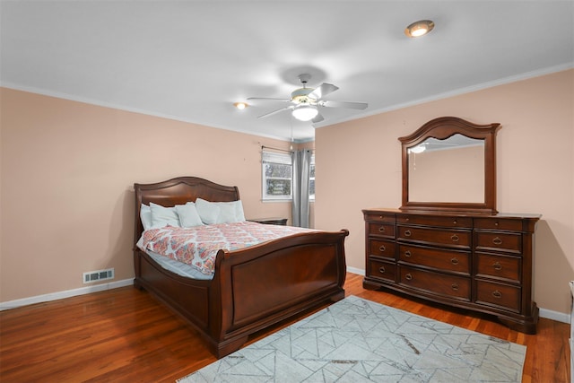 bedroom featuring crown molding, wood finished floors, visible vents, and baseboards