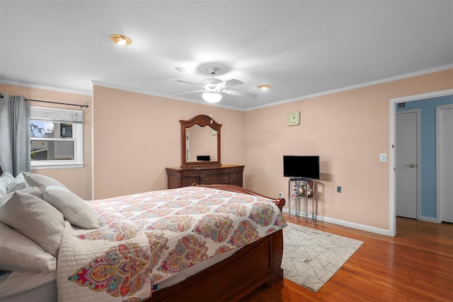 bedroom with crown molding, wood finished floors, baseboards, and ceiling fan