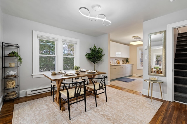 dining space featuring a baseboard heating unit, sink, and light hardwood / wood-style floors