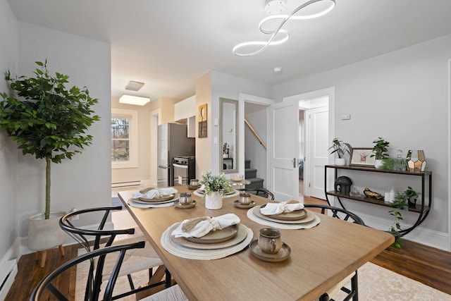 dining space with dark hardwood / wood-style flooring and a baseboard heating unit