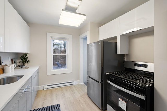 kitchen featuring sink, white cabinetry, baseboard heating, stainless steel appliances, and light hardwood / wood-style floors