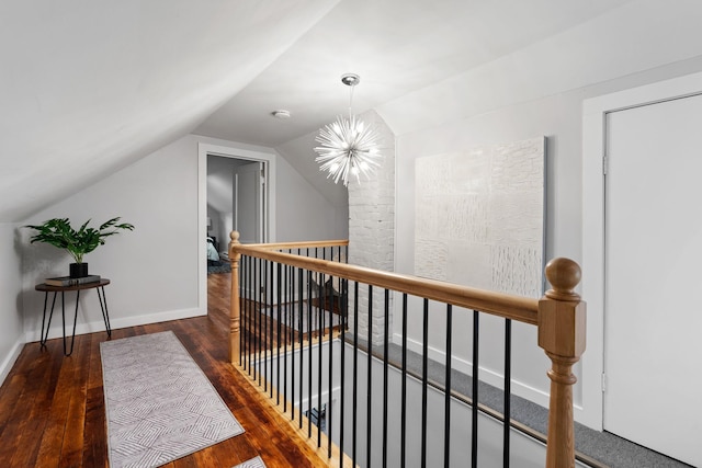 corridor featuring dark wood-type flooring, vaulted ceiling, and a notable chandelier