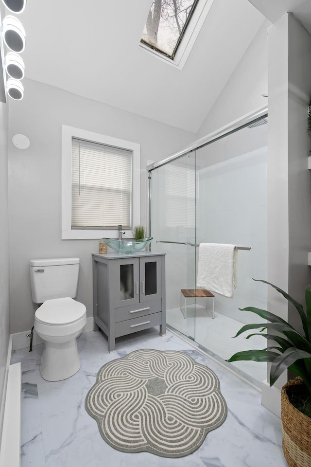 bathroom with vanity, a shower with shower door, lofted ceiling with skylight, and toilet