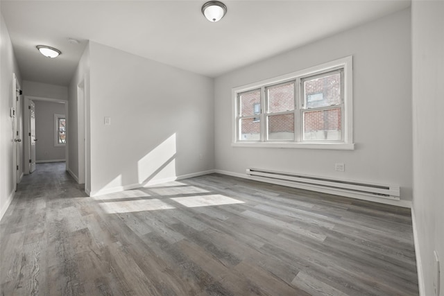 spare room featuring a baseboard radiator, light hardwood / wood-style floors, and a wealth of natural light