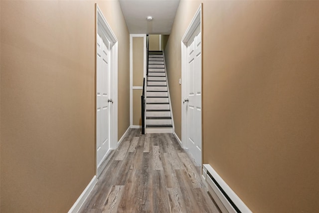 hall with a baseboard heating unit and light hardwood / wood-style flooring