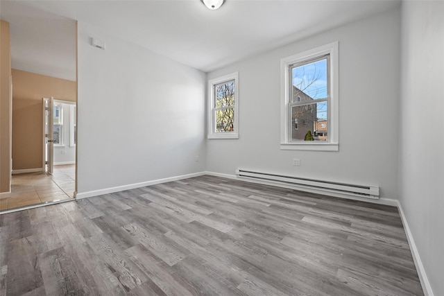 unfurnished room featuring light wood-type flooring and baseboard heating