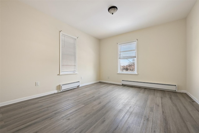 empty room featuring a baseboard heating unit and hardwood / wood-style flooring