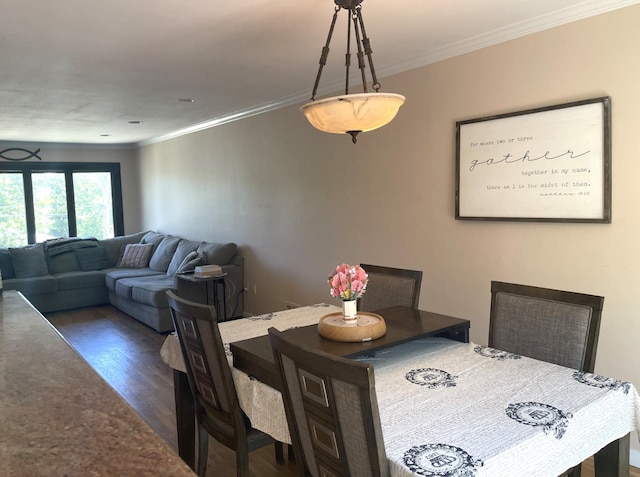 dining area featuring dark wood-type flooring and ornamental molding