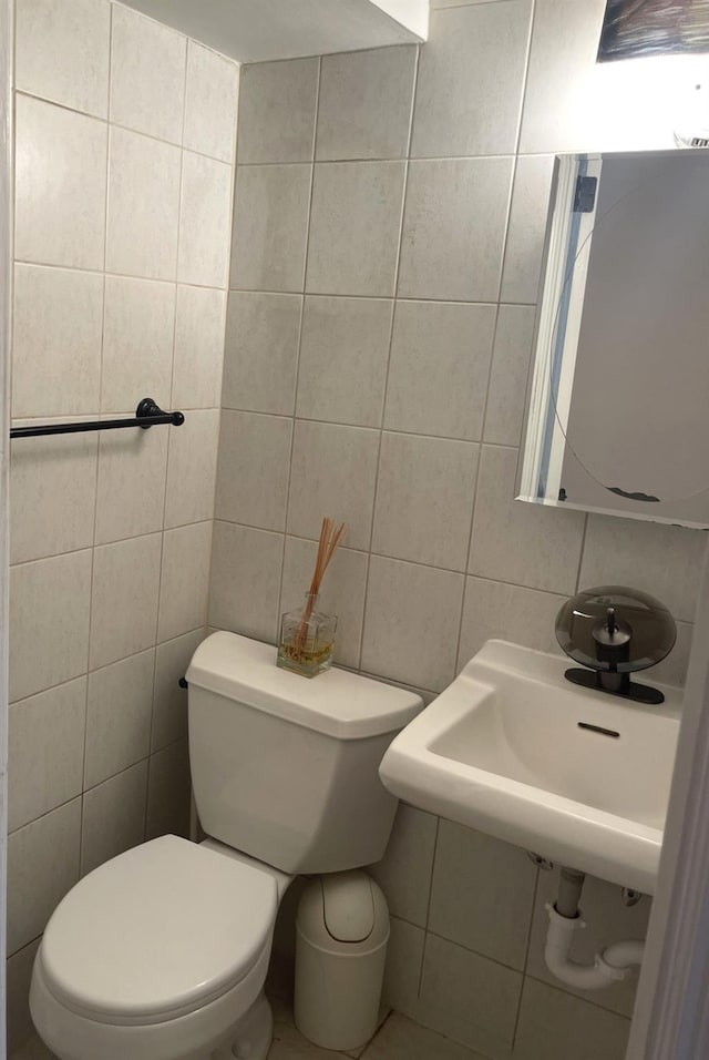 bathroom with tasteful backsplash, sink, tile walls, and toilet